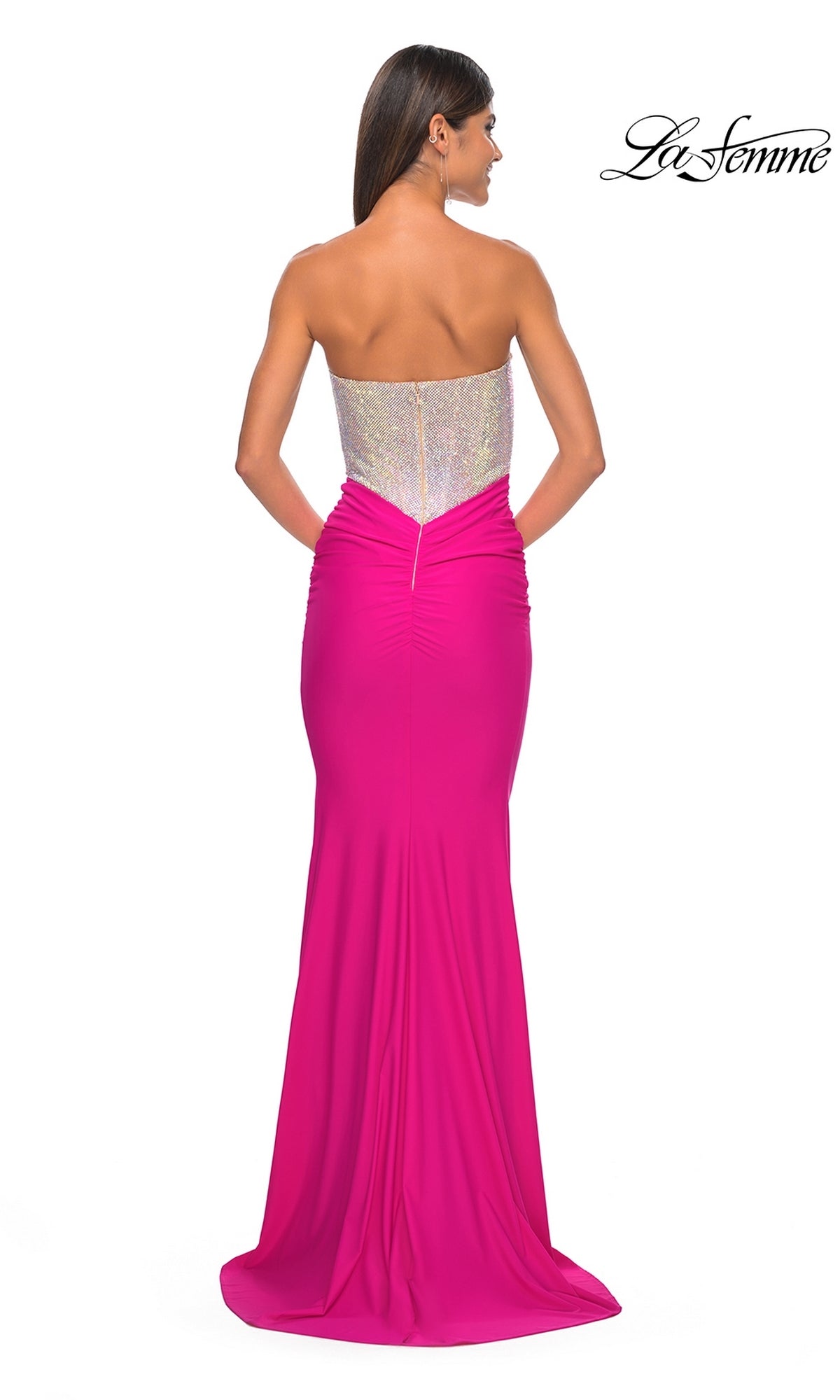 A woman faces away in the Strapless Hot Pink Long Prom Dress: La Femme 32440, featuring a sequined bodice and floor-length skirt. The